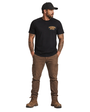 Man wearing a black t-shirt with a logo, brown pants, and boots on a white background