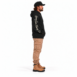 Heavy Machinery Dept. Premium Hoodie in black — full-length left sleeve model mockup, hands in pocket, Heavy Iron at shoulder and Filming Co. toward cuff